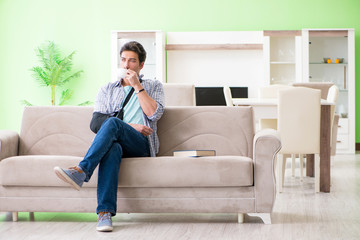 Obraz premium Young student man with hand injury sitting on the sofa 