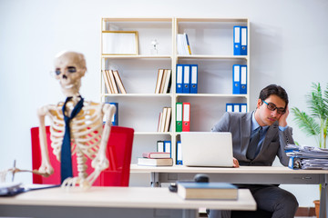 Businessman working with skeleton in office