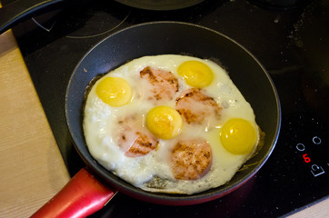 ham with eggs fried in a frying pan.