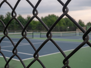 Tennis courts in background with black fence framing in foreground