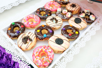 Donut variety on white tray outdoor daylight colourful sweet desert
