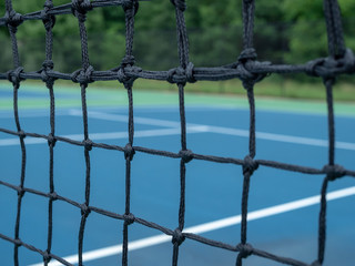 Zoomed view of tennis court net mesh with blurry courts in background 