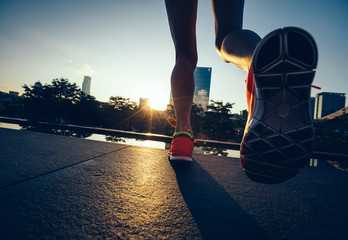 Healthy lifestyle woman runner legs running on sunrise city