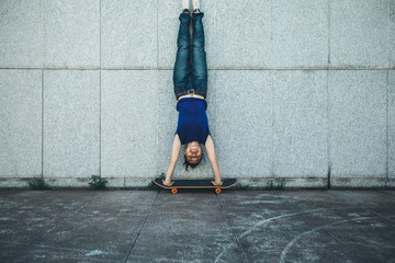 Fototapeta na wymiar Sportswoman doing a handstand against a marble wall