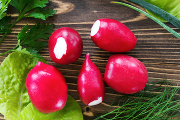 Fresh radishes with green onions,parsley and lettuce on a wooden background