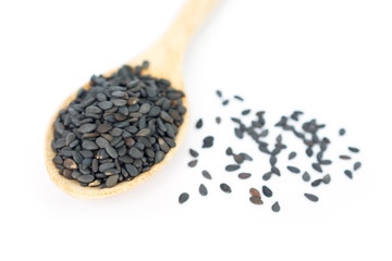 Heap of black sesame on wooden spoon on white background.