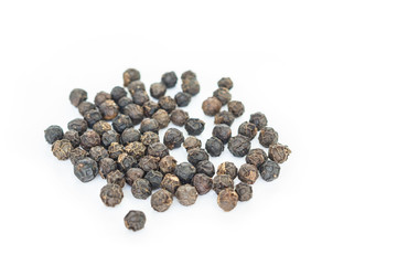 black peppercorns heap on white background.