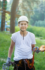 cute boy  in white t shirt in the adventure activity park with helmet and safety equipment. Young boy playing and having fun doing activities outdoors. Hobby, active lifestyle concept