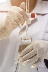 close up of hands are holding the burette and flask in chemistry laboratory.