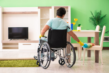 Fototapeta premium Disabled man on wheelchair cleaning house