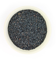 Black sesame in white bowl on white background top view.