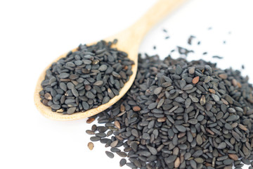 Heap of black sesame on wooden spoon on white background.