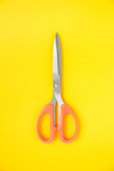 orange scissors cutting on yellow background