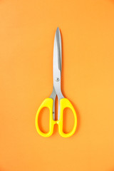 yellow scissors cutting on orange background