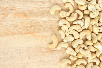 heap cashews top view frame or border on wooden background.