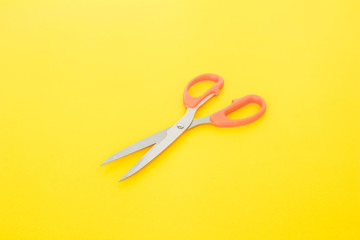 orange scissors cutting on yellow background