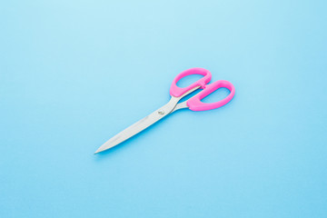 pink scissors cutting on blue background