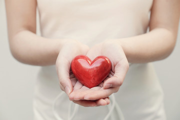 Young woman holding red heart, health insurance, donation, organ donor, compassion concept