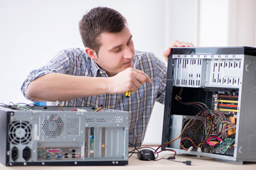 Young technician repairing computer in workshop