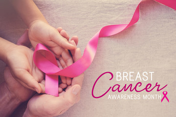 Adult and child hands holding pink ribbons, Breast cancer awareness, abdominal cancer awareness and...