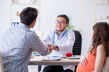 Fototapeta premium Pregnant woman with her husband visiting the doctor in clinic