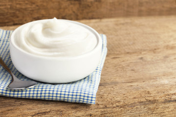 Healthy flavored yogurt in ceramic bowl and spoon on cloth with wood background with copy space for your text.