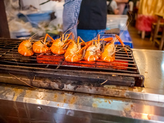 Grilled giant river prawn or big shrimp on stove with selective focus.A recommended menu for tourists when they come to Thailand. The prawn is served with spicy seafood sauce.