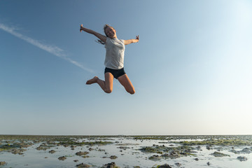 junges Mädchen springt im Wattenmeer der Nordsee vor Freude in die Luft