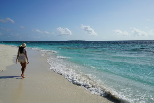 Young woman walking along the beach in the Maldives