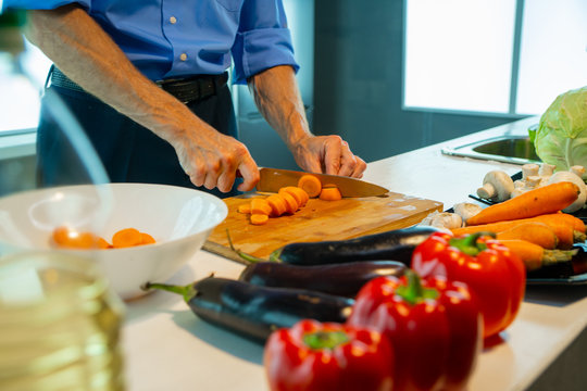 A man on a board cuts carrots