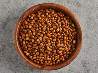 Top view of wooden bowl of salted fried soy beans, isolated on grey background