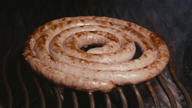 UHD 60 fps shot of the delicious homemade meat sausages frying on the grill