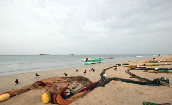 Small fishing boat next to fishing nets drying on Nilaveli beach in Trincomalee Sri Lanka Asia