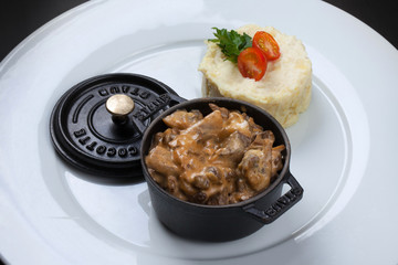 Mushrooms and chicken wings in a creamy sauce in a black pot