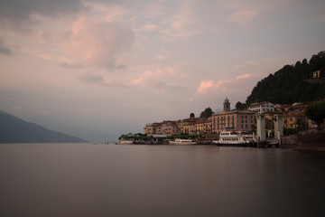 Obraz premium bellagio at sunset long exposure with boat and ferry at cloudy sunset