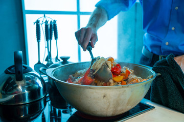 A man in a saucepan stirs hot food