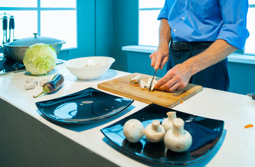 Obraz na płótnie Canvas In the kitchen, a man cuts vegetables