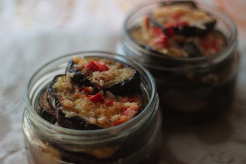 two glass jars with fried eggplants, ground garlic, red chili