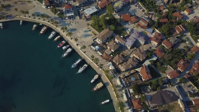 Top view of the moored ships. The drone flies forward. The ships is swaying on the waves. On the shore, low houses.
