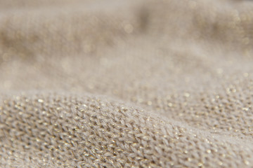 Close-up industrial knitted textile in beige and gold colors as background