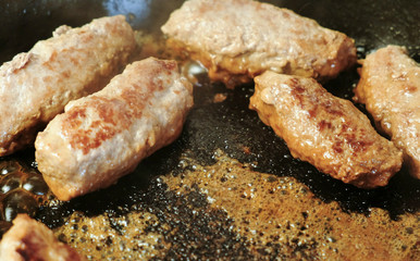 Tasty meat cutlets are fried in oil in a pan. Close-up top view.