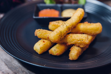 Seasoning French fries served with mayonnaise and thousand island sauce in black plate.