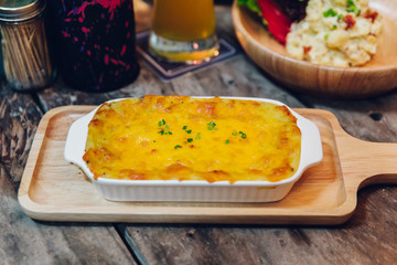 Hot baked lasagne with cheese melting surface served in wooden plate.