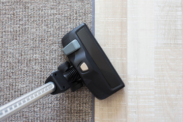 housekeeping concept - modern vacuum cleaner over carpet and wooden parquet floor