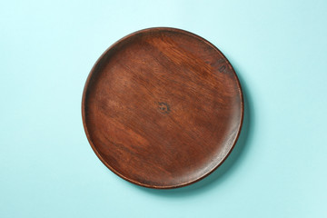 Wooden plate on blue background, from above