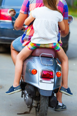 Father and daughter riding a retro scooter in the street wearing hats. Holiday and travel family concept