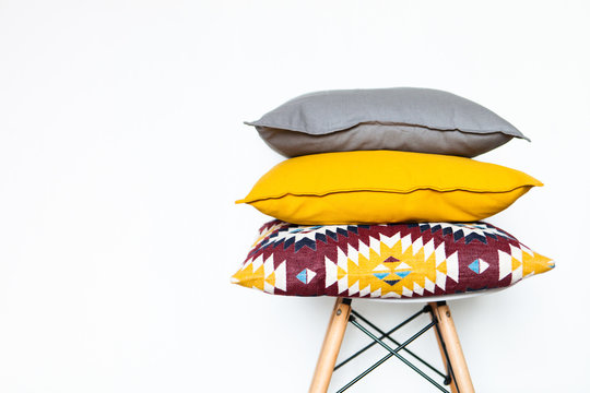 Cushions on the chair white wooden background close up with copy space. Sweet home and cozy concept