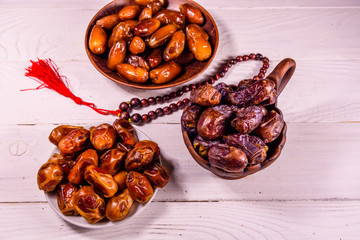 Date fruits and rosary on wooden table