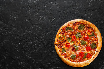 Pizza with Mozzarella cheese, Ham, Tomatoes, pepper, Spices and Fresh Basil pesto sauce. Italian pizza.on black background. with copy space. top view