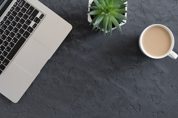 Top view of modern dark office desk table with computer laptop and cup of coffee, flat lay with copy space.
